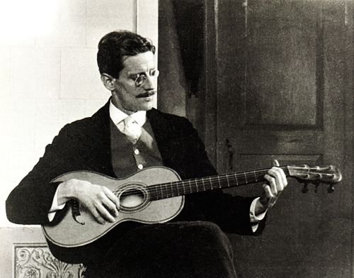 Image: photo of modern litearture's James Joyce playing guitar by Ottocaro Weiss, 1915 [PD-1996].